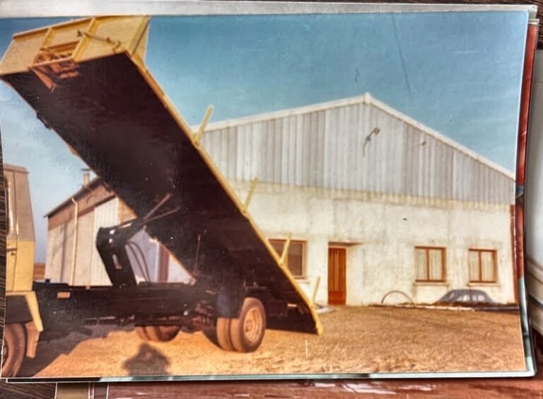 Photographie d'archive — benne en position haute devant un bâtiment industriel
