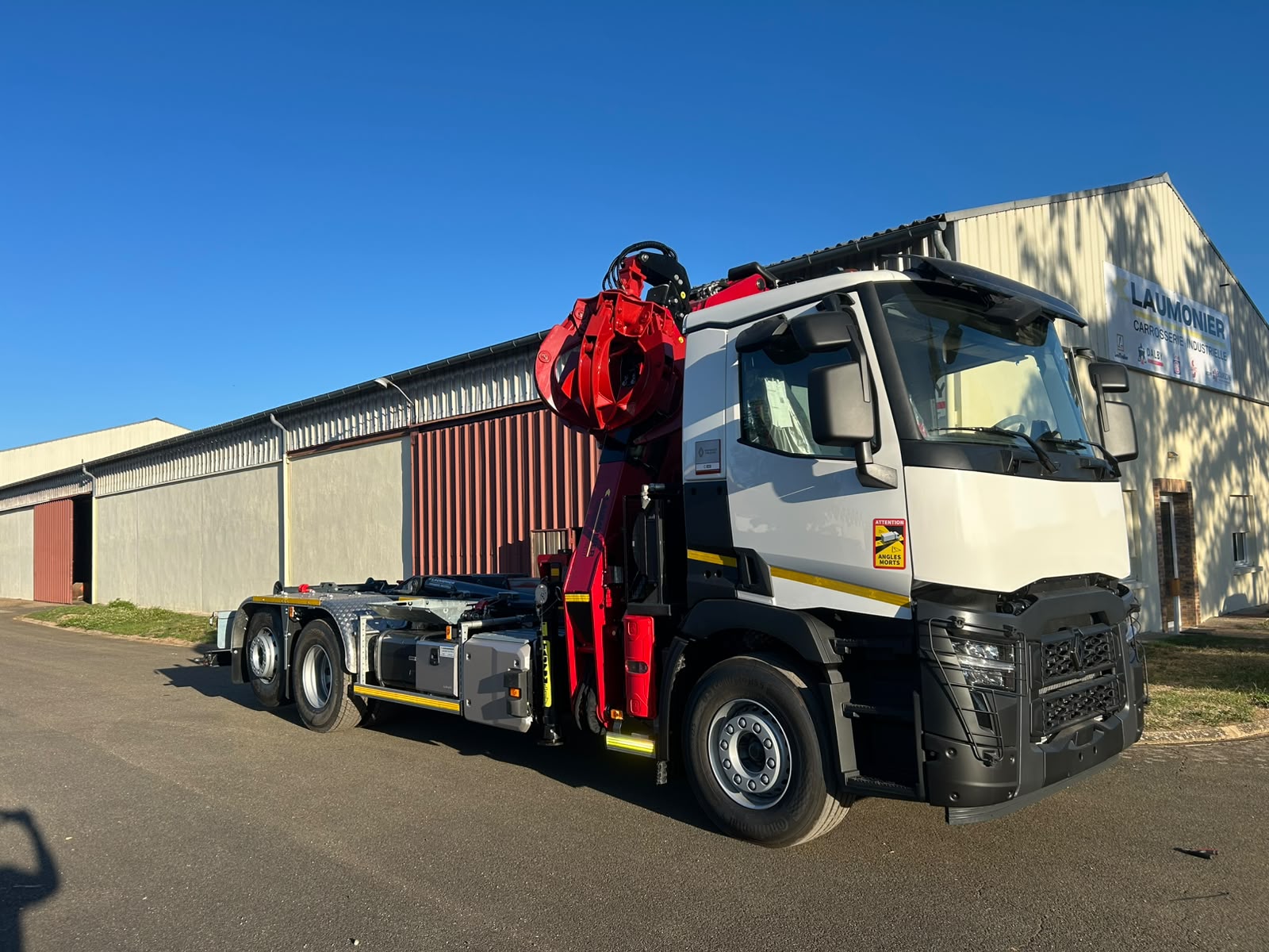 Porteur 8x4 équipé d'une grue auxiliaire et d'un bras ampliroll